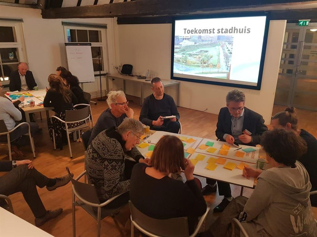  Inwoners en ambtenaren praten aan een tafel tijdens een bijeenkomst over Toekomst Stadhuis in maart 2020. 