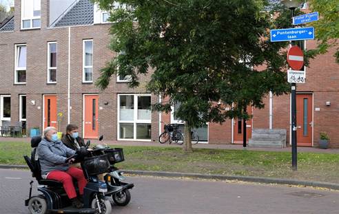  Twee inwoners met een mondkapje rijden in scootmobiels in de Puntenburgerlaan 